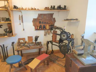 Ein traditioneller Schuhmacherraum mit verschiedenen Werkzeugen und Maschinen. An der Wand sind zahlreiche Utensilien zur Schuhherstellung ausgestellt.