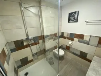 Ein modernes Badezimmer mit einer begehbaren Dusche und stilvollen Fliesen in verschiedenen Farben. An der Wand hängt ein schwarzes und weißes Bild.