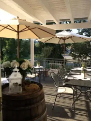 Eine gemütliche Terrasse mit Sonnenschirmen und Tischen. Im Hintergrund sind Pflanzen und eine angenehme Atmosphäre zu sehen.