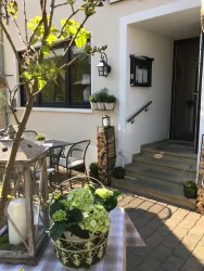 Ein einladender Eingangsbereich mit einem dekorativen Tisch, Pflanzen und einer Laterne. Die Treppe führt zur Eingangstür eines Hauses.