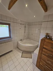 Ein modernes Badezimmer mit einer halbrunden Badewanne und weißen Fliesen. Das Zimmer hat Holzbe元素, ein Fenster und einen stylischen Holzschrank.