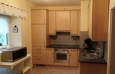 Eine moderne Küche mit hellen Holzmöbeln und einer freundlichen Atmosphäre. Sie enthält einen Herd, eine Spüle und einen Mikrowellenherd.