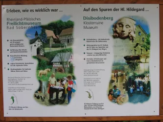 Ein Informationsschild über das Freilichtmuseum Bad Sobernheim und den Disibodenberg. Es zeigt verschiedene Aktivitäten und kulturelle Aspekte der Region.