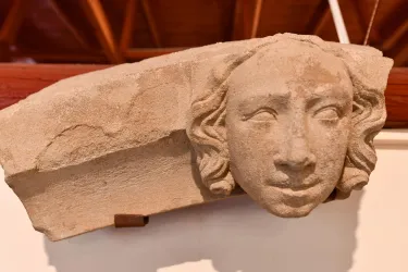Ein antikes Steinrelief mit dem Kopf einer Frau. Die Darstellung zeigt detaillierte Merkmale und Haarsträhnen.