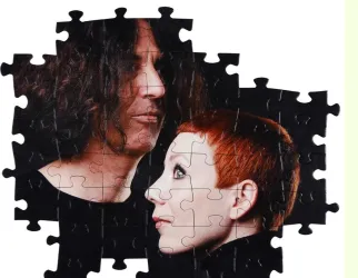 Ein Puzzlespiel zeigt die Gesichter von zwei Personen, die sich ansähen. Der Hintergrund ist schwarz, was die Figuren hervorhebt.