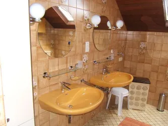 Ein Badezimmer mit zwei gelben Waschbecken und großen, runden Spiegeln. Die Wände sind mit eleganten Fliesen in warmen Farbtönen ausgekleidet.
