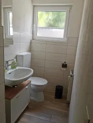 Ein modernes kleines Badezimmer mit einem Waschbecken und einer Toilette. Es hat helle Wände und einen großen Fensterblick.