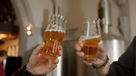 Zwei Gläser Bier werden in die Höhe gehalten. Die Stimmung scheint festlich und gesellig zu sein.