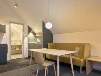 Ein modernes Wohnzimmer mit einem Essbereich und einer gemütlichen Couch. Die Einrichtung ist hell und freundlich, ideal für eine entspannte Atmosphäre.