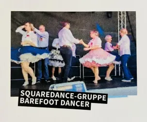 Eine Gruppe von Tänzern führt einen Square Dance auf einer Bühne auf. Sie tragen bunte Kleider und tanzen zusammen mit Freude.