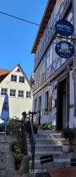 Ein charmantes Hotel mit einem historischen Fachwerkhaus und klar blauem Himmel. Die Umgebung ist einladend und gepflegt.