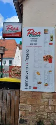 Ein Restaurant-Schild mit der Aufschrift "Pisa" und einer Speisekarte für Pizzas und andere Speisen. Das Schild ist an einer Wand angebracht und hat eine ansprechende Gestaltung.
