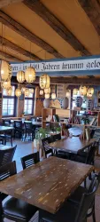 Ein gemütliches Restaurant mit Holzdekor und stilvollen Lampen. Die Tische sind bereit für Gäste in einladender Atmosphäre.