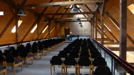 Ein heller Saal mit Holzdecke und vielen Stühlen. In der Mitte steht ein Klavier, bereit für eine Aufführung.