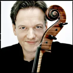 Ein Musiker mit einem charmanten Lächeln, der eine Violine hält. Der Hintergrund ist neutral und hebt die Darstellung des Künstlers hervor.