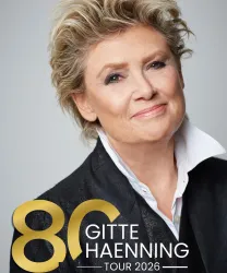 Eine Porträtaufnahme einer lächelnden Frau mit blonden, lockigen Haaren. Im Vordergrund steht "80 GITTE HAENNING TOUR 2026".