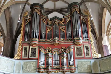 Eine große Orgel mit prächtigen Verzierungen in einer Kirchenstruktur. Die Rohre sind kunstvoll angeordnet und tragen zur beeindruckenden Atmosphäre des Raumes bei.