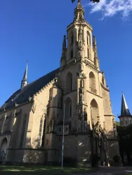 Eine beeindruckende Kirche mit einem hohen Turm und gotischen Elementen. Der klare blaue Himmel ergänzt die majestätische Architektur.