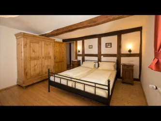 Ein gemütliches Schlafzimmer mit einem Doppelbett und Holzvertäfelungen. Der Raum verfügt über einen Kleiderschrank und warme Beleuchtung.