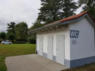 WC-Anlage im Hintergrund der Wohnmobilstellplatz