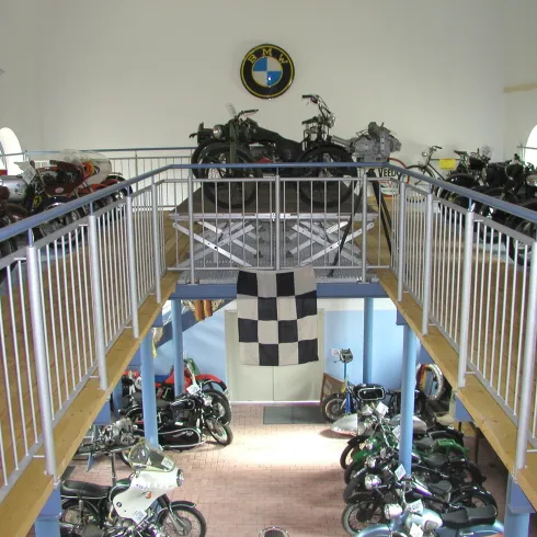 Ein Motorrad-Museum mit mehreren Etagen, das eine Vielzahl von Motorrädern zeigt. Im Hintergrund hängt ein BMW-Symbol an der Wand.
