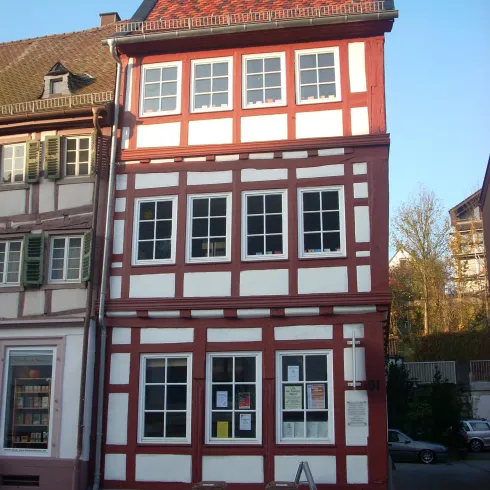 Ein historisches Fachwerkhaus mit rotem und weißem Holzrahmen. Es zeigt eine faszinierende Architektur in einer Stadtansicht.