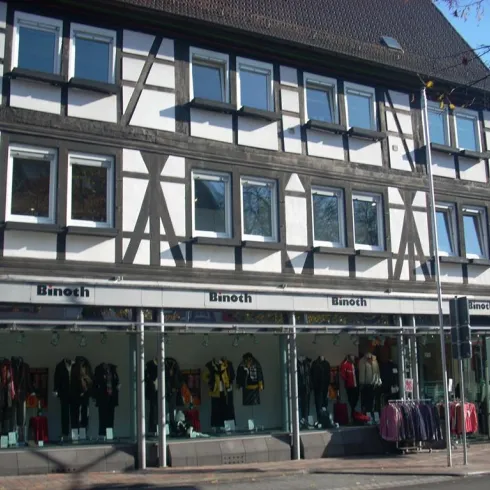 Ein modernes Geschäft mit einer Fassade im Fachwerkstil. Im Schaufenster werden verschiedene Kleidungsstücke ausgestellt.