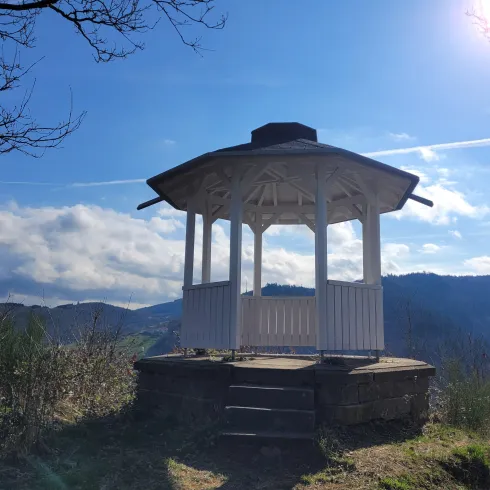 Ein schöner Pavillon auf einem Hügel mit Blick auf die umliegende Landschaft. Der Himmel ist klar und die Sonne scheint.