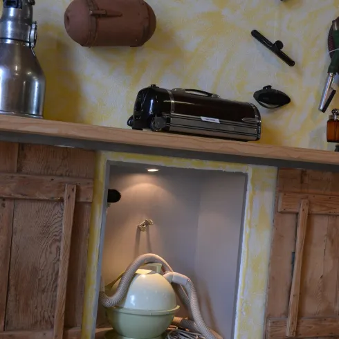 Ein Wandschrank mit verschiedenen Küchengeräten und einer schönen, pastellfarbenen Wand. In einer Nische ist eine Retro-Küchenmaschine zu sehen.